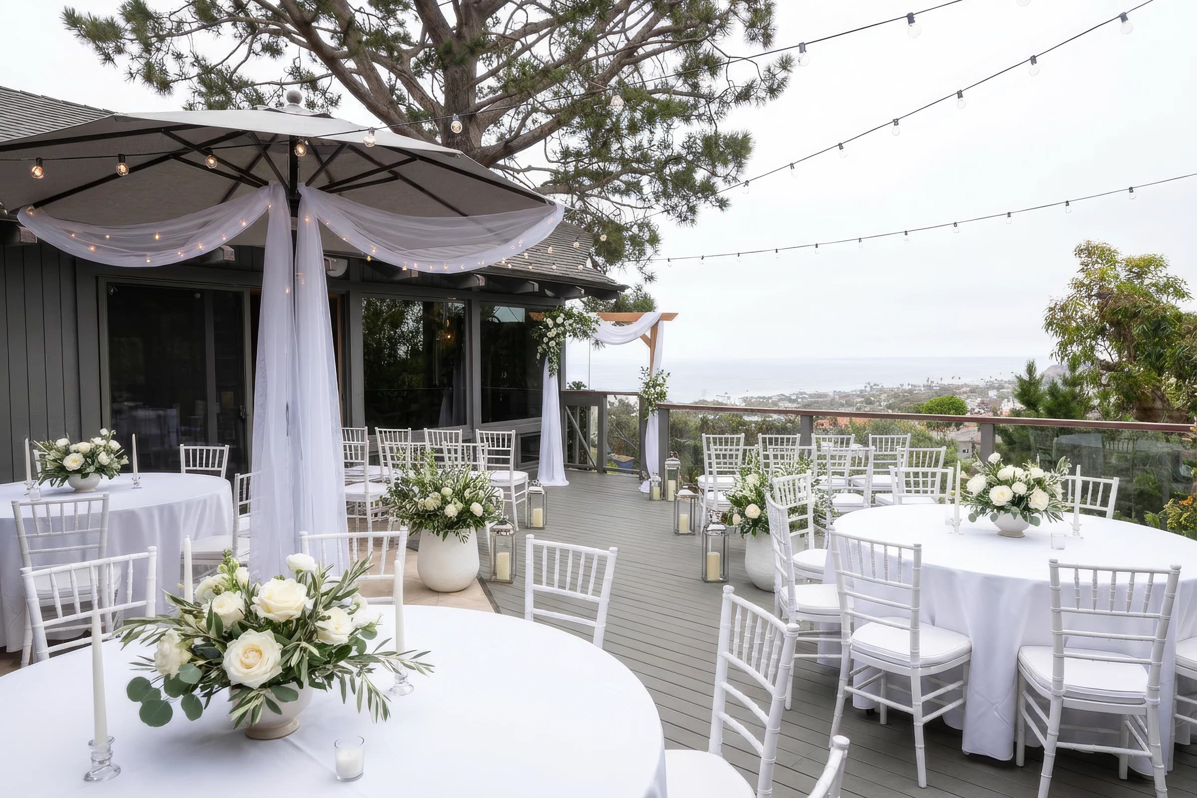 A coastal wedding ceremony terrace with white flowers and an ocean view