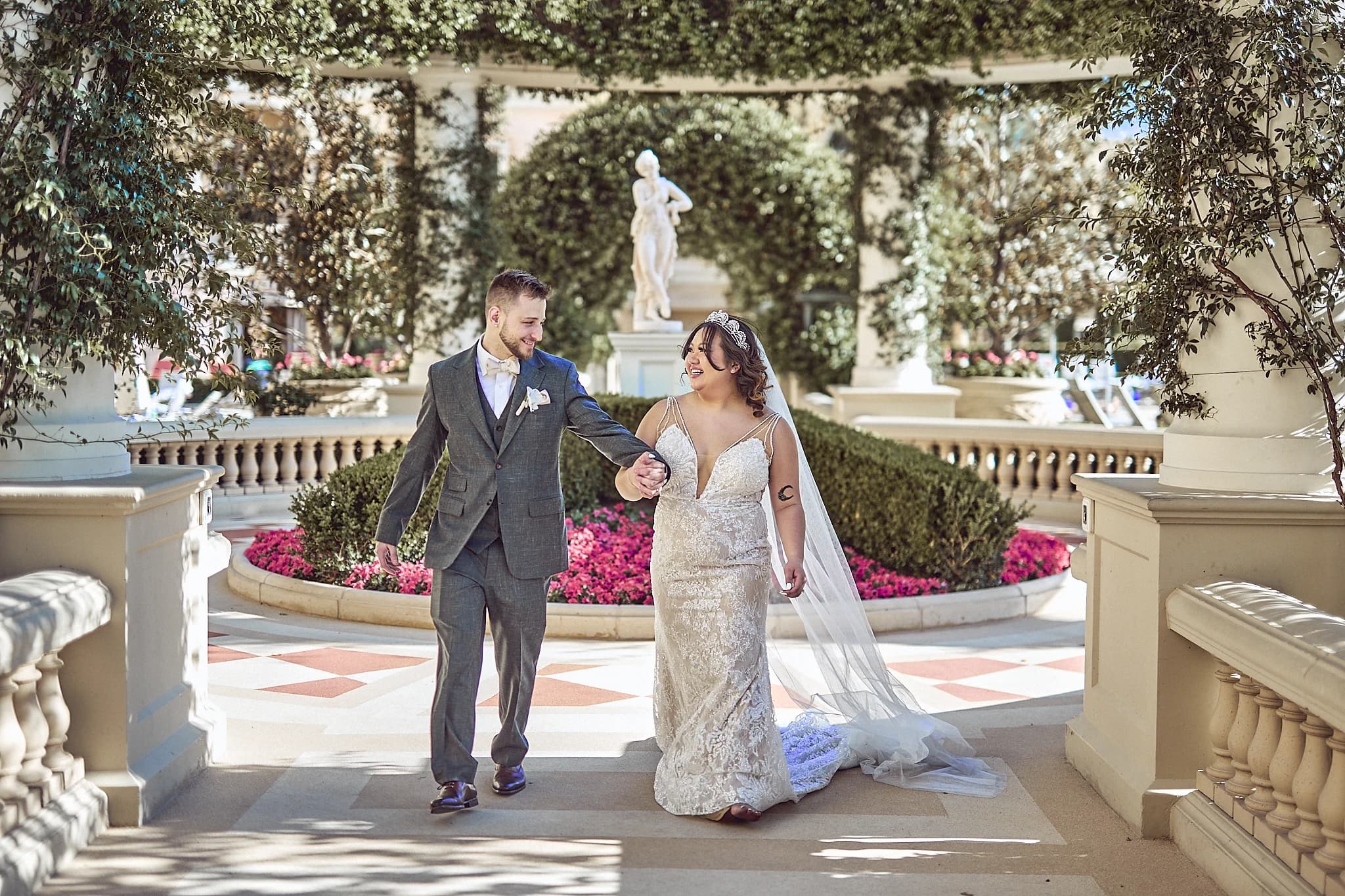 Newlyweds walk hand in hand through an elegant Las Vegas garden